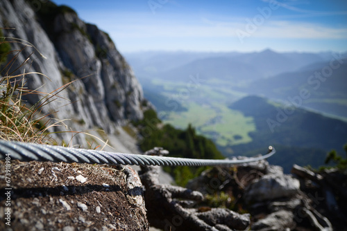 Stahlseil eines Klettersteigs mit Bergpanorama im Hintergrund photo