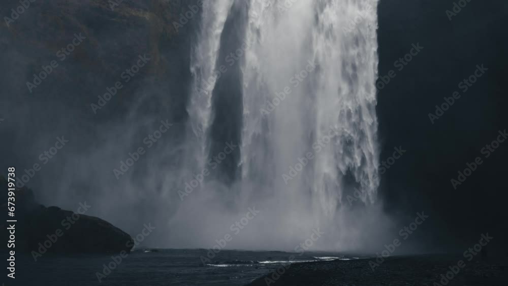 Awe-inspiring Skogafoss waterfall. Icelandic natural wonder with majestic waterfall and rugged surroundings. Suggestive 4k cinematic footage in slow motion. Cold water, cloudy sky, Nordic atmosphere.