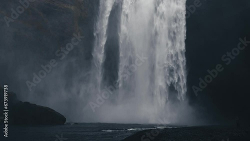 Awe-inspiring Skogafoss waterfall. Icelandic natural wonder with majestic waterfall and rugged surroundings. Suggestive 4k cinematic footage in slow motion. Cold water, cloudy sky, Nordic atmosphere. photo