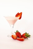 Vertical shot of a strawberry smoothie with two slices on the rim of the glass and net to the glass