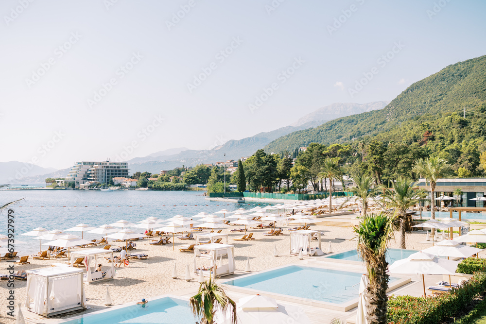 Luxurious sandy beach with sun loungers and white parasols at the One and Only Hotel. Portonovi, Montenegro