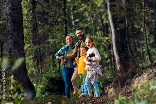 Portrait of smiling family of four exploring nature on a scenic forest hike.