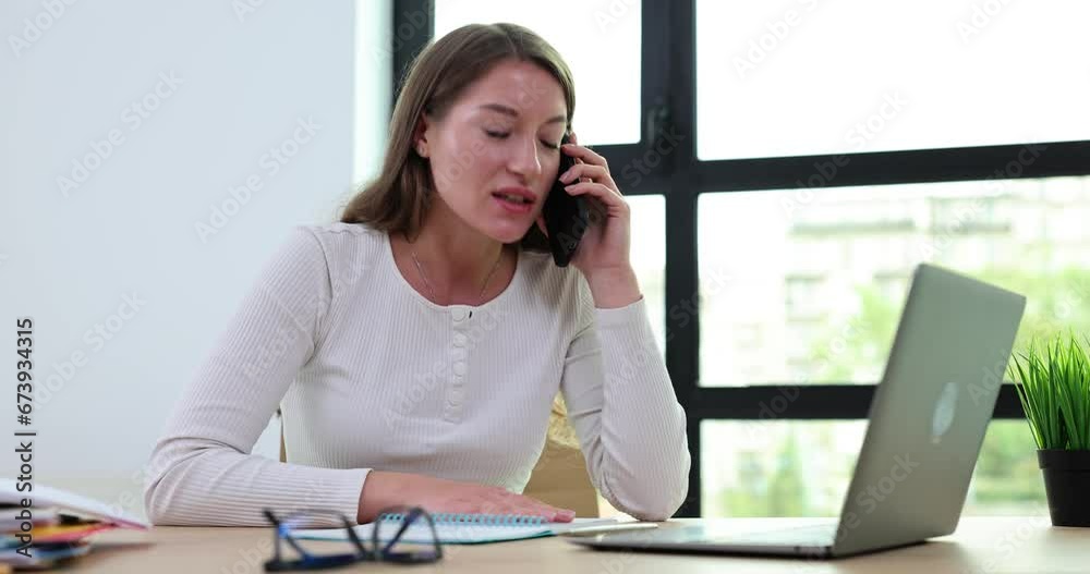 Angry businesswoman talking on phone and looking at laptop screen