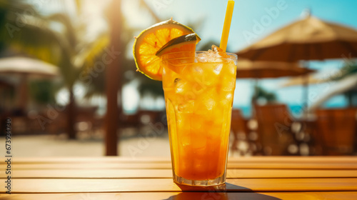 A tropical cocktail with orange slices on a wooden table on the beach.