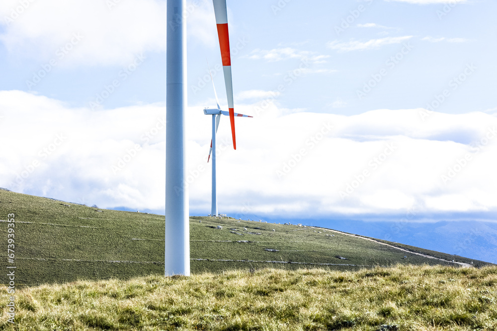 Wind farm with turbines on the mountains. Eco-sustainable industry with nature-friendly technologies for clean energy in a better environment. Conceptual mountainous landscape for renewable
