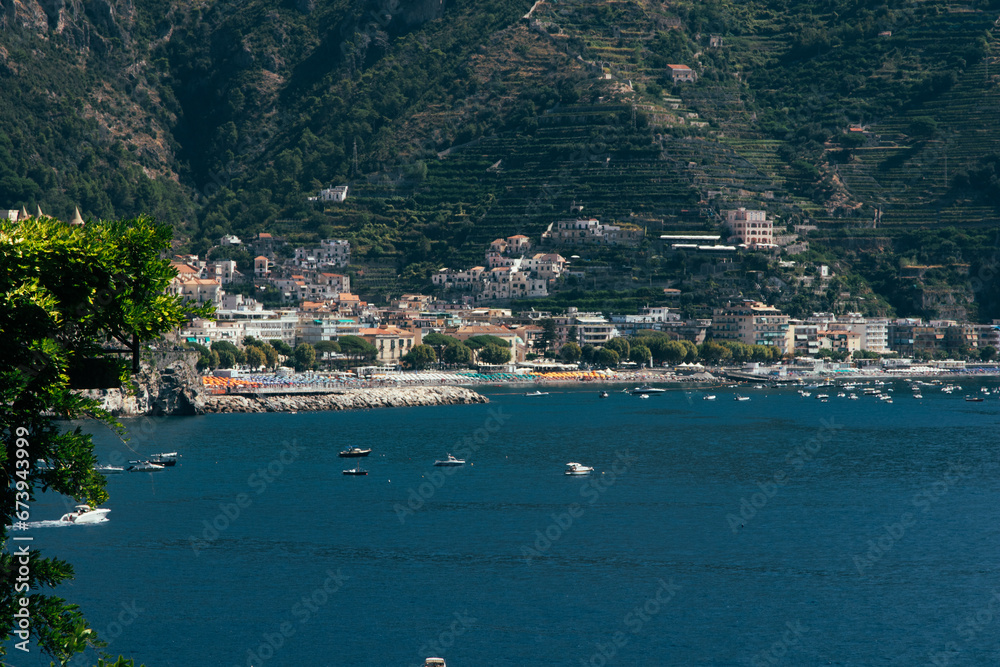 Amalfi Sea Coast with Umbrellas, people swim, and Yachts. Clean and blue sea where to swim. Photo for tourism and summer background. Concept of vacation and beach life in the open air  