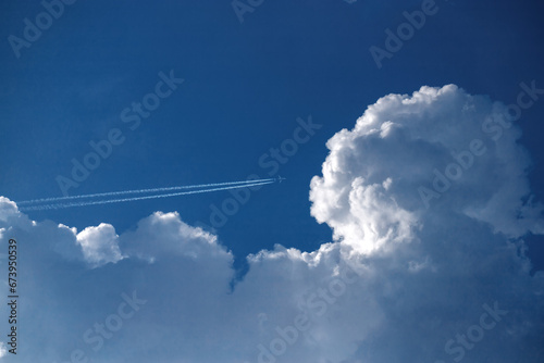 Airplane flying in the blue sky among clouds.
