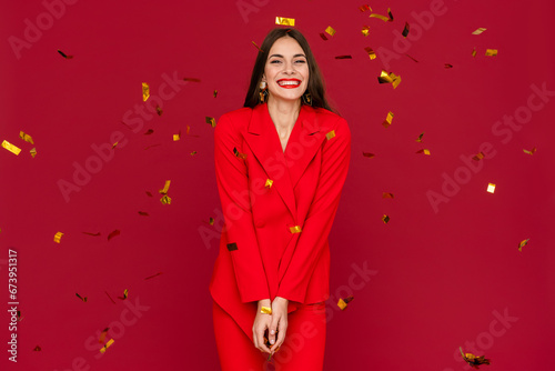 attractive woman celebrating Christmas on red background in confetti