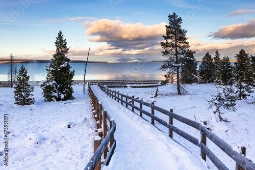 Snow-covered winter landscape and boardwalk at sunset in the West Thumb Geyser are a of Yellowstone Lake in Yellowstone National Park Wyoming.