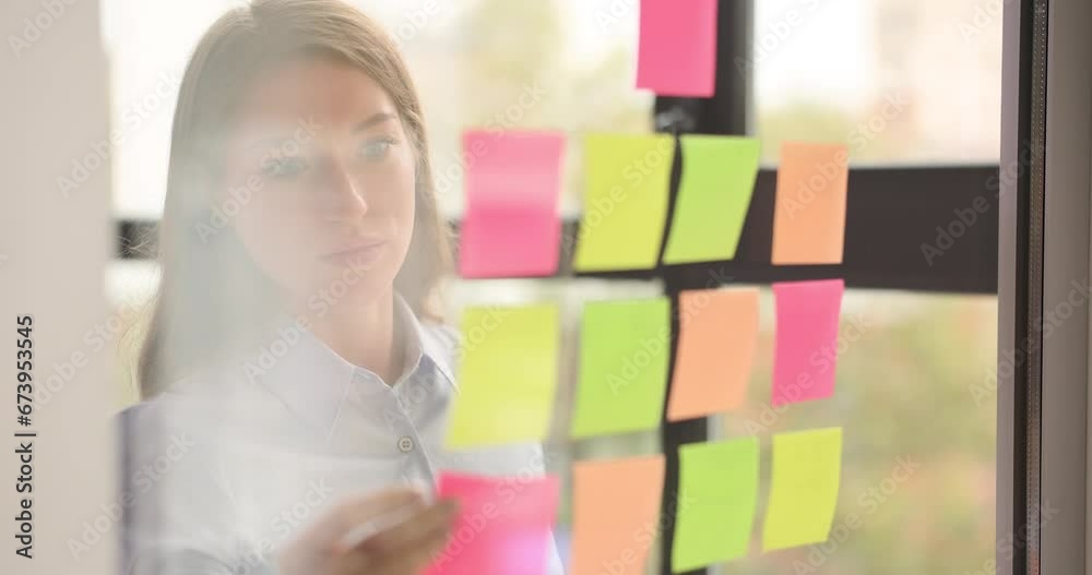 Seo or creative business manager sticking sticky notes to glass wall and whiteboard for sharing ideas in office