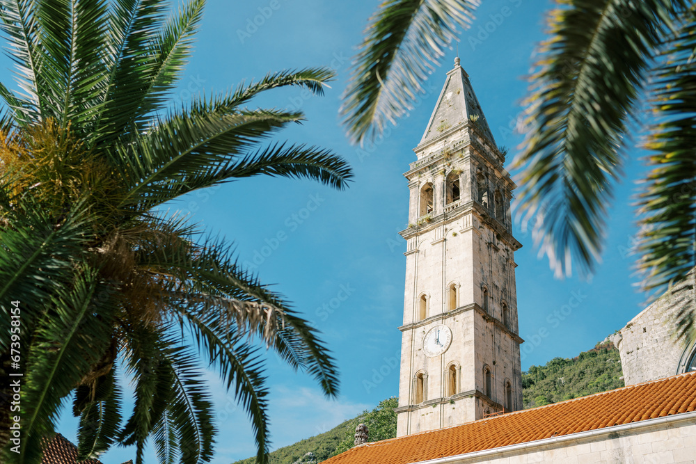 View through the branches of a tree to the bell tower of the Church of St. Nicholas in Perast. Montenegro