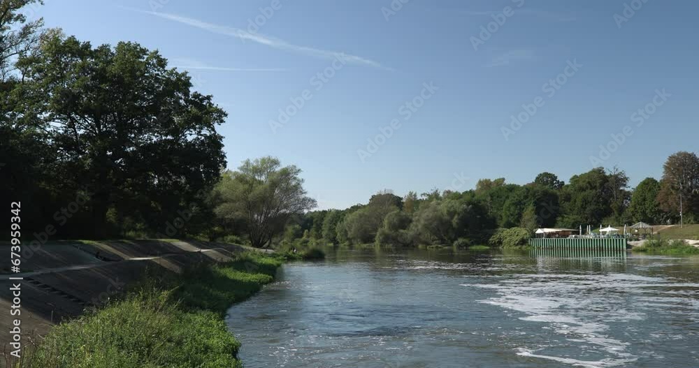 Green river bank, concrete reinforcements of the riverbed, agitated flowing water, green trees around the riverbed, slow motion Green river bank, concrete reinforcements of the riverbed, agitated flowing water, green trees around the riverbed, slow motion