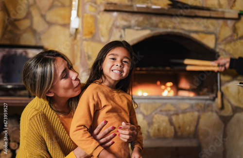 Happy latin mother and daughter having tender moment at house patio during barbecue dinner