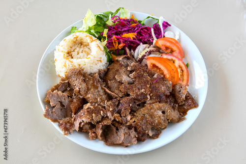 Turkish and Arabic Traditional Ramadan doner kebab with tasty tomato sauce and rice or turkish pilav in white plate on wood table background. ( Pilav ustu et doner, Hatay tavuk doner iskender kebap ) photo