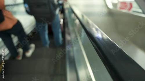 Close up of rubber handrail belt strap of moving down escalator with blurred people in the background. photo