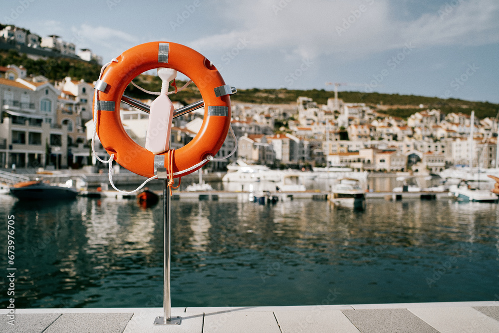 Orange lifebuoy on a stand on the coast of Lustica Bay. Montenegro