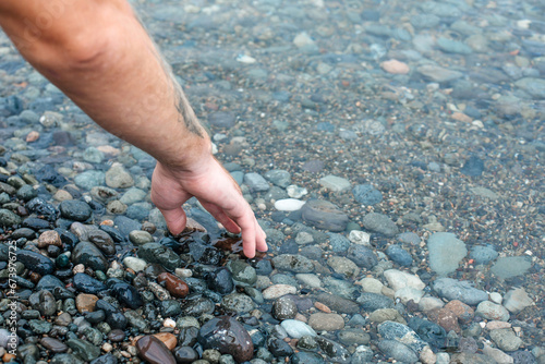 Athletic man collecting stones on the seashore