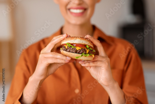 Close-up of woman s smile as she holds delicious burger