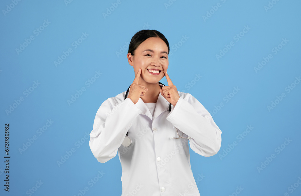 Happy Asian Doctor In Uniform Pointing At Her Smile With Two Hands Happy Asian Doctor In Uniform Pointing At Her Smile With Two Hands