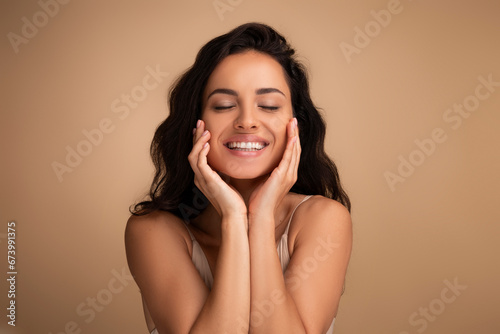 Joyful woman with closed eyes touching her face