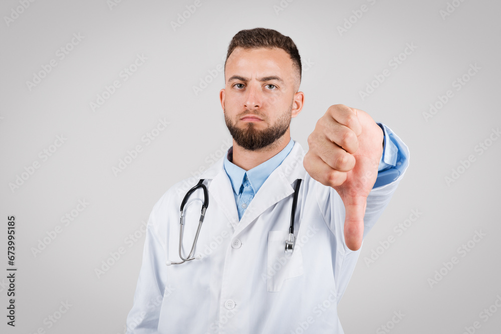 Male doctor showing disapproval with a thumbs-down gesture Male doctor showing disapproval with a thumbs-down gesture