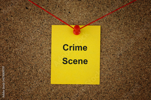 A yellow paper note with the words Crime Scene on it pinned to a detective board with red threads. Close up.