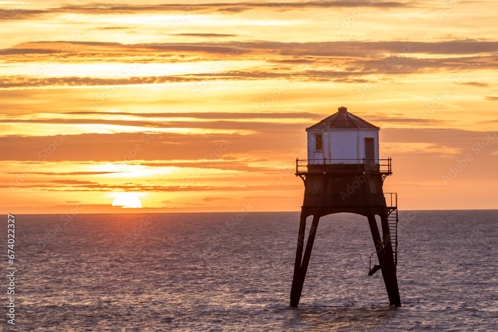 sunrise over a old lighthouse in the sea, Dovercourt low lighthouse, built in 1863 and discontinued in 1917 and restored in 1980 the 8 meter lighthouse is still a iconic sight, October 2023