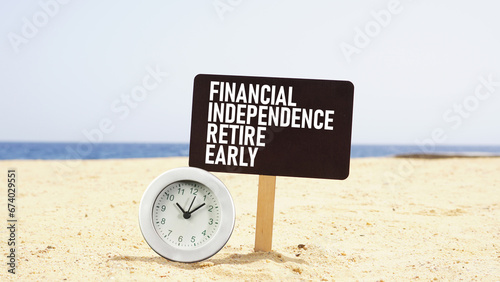 Financial independence retire early FIRE is shown using the text and photo of the clock on the beach photo