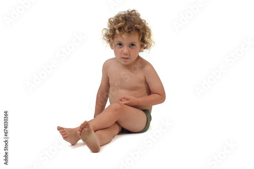 boy in underpants sitting on the floor looking at camera and cross legged on white background (3 year old)