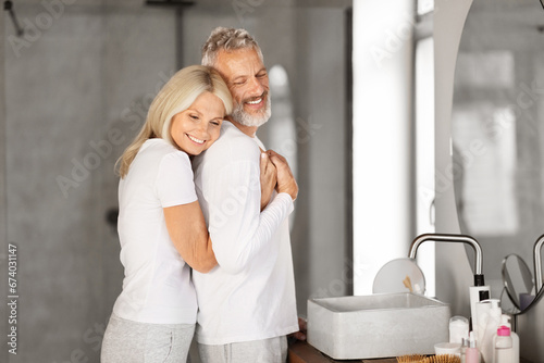 Happy Together. Loving Mature Couple Embracing In Bathroom Interior