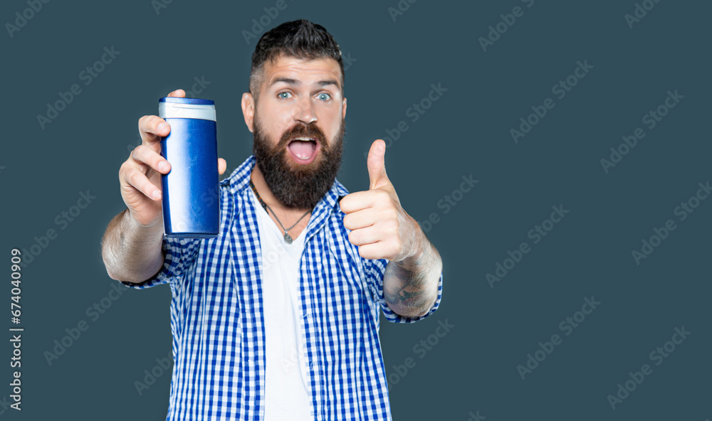 bearded guy hold male product of beard care cosmetics. thumb up bearded guy hold male product of beard care cosmetics. thumb up
