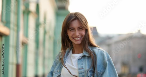 Happy woman in denim outfit walking in the street, turning in happiness.
