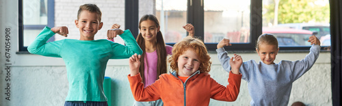 four cute little children in sportswear playing muscles and smiling at camera, child sport, banner photo
