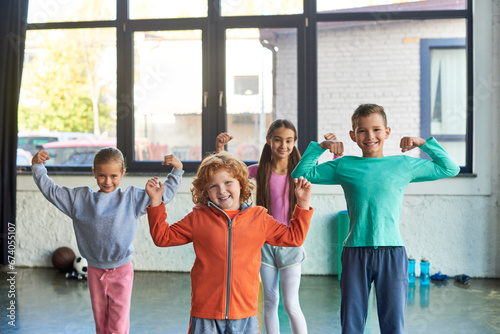 Εκτύπωση καμβά four pretty little children in sportswear playing muscles and smiling at camera,