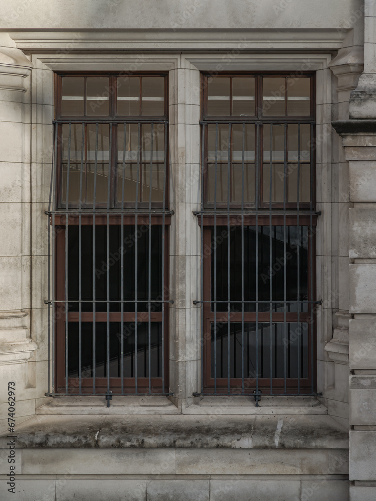 Glass window frame with behind bars exterior of ancient building. Wooden window with glass and protective grille, A barred window on old wall, Space for text, Selective focus.
