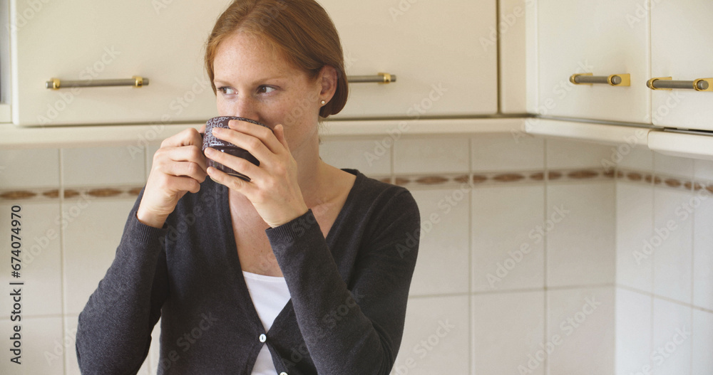 Redhead woman relaxing with coffee or tea in a kitchen