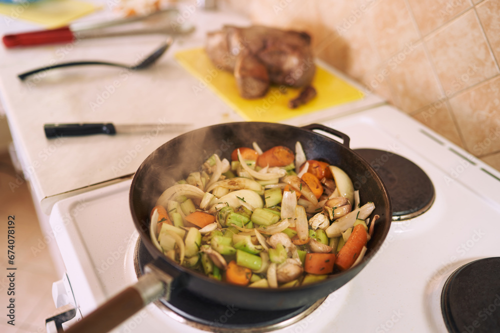 Steam rises from chopped vegetables stewed in a frying pan on the stove