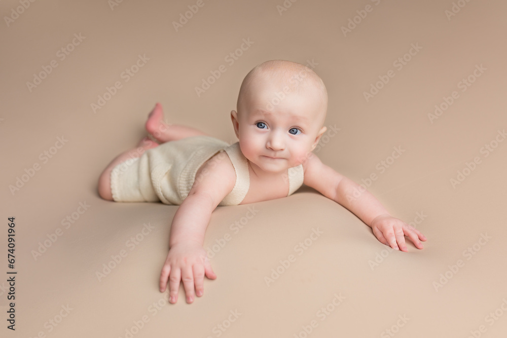 a small child lies on a light background. newborn boy. baby's first photo shoot a small child lies on a light background. newborn boy. baby's first photo shoot