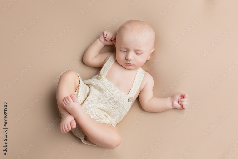 a small child lies on a light background. newborn boy. baby's first photo shoot a small child lies on a light background. newborn boy. baby's first photo shoot