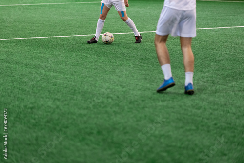 Five-a-side soccer players playing game in indoor stadium on artificial turf.