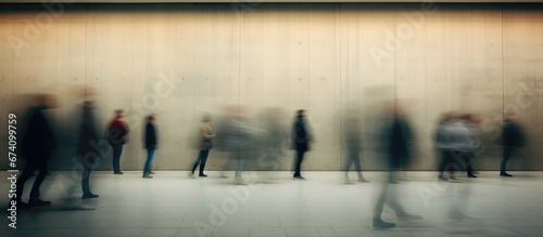 People hurry about their business against the backdrop of a city concrete wall. Long exposure. Motion blur. Abstract background.