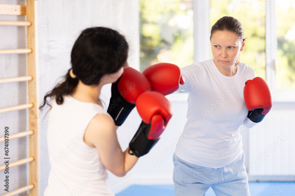 Adult woman and young woman training boxing punches in studio