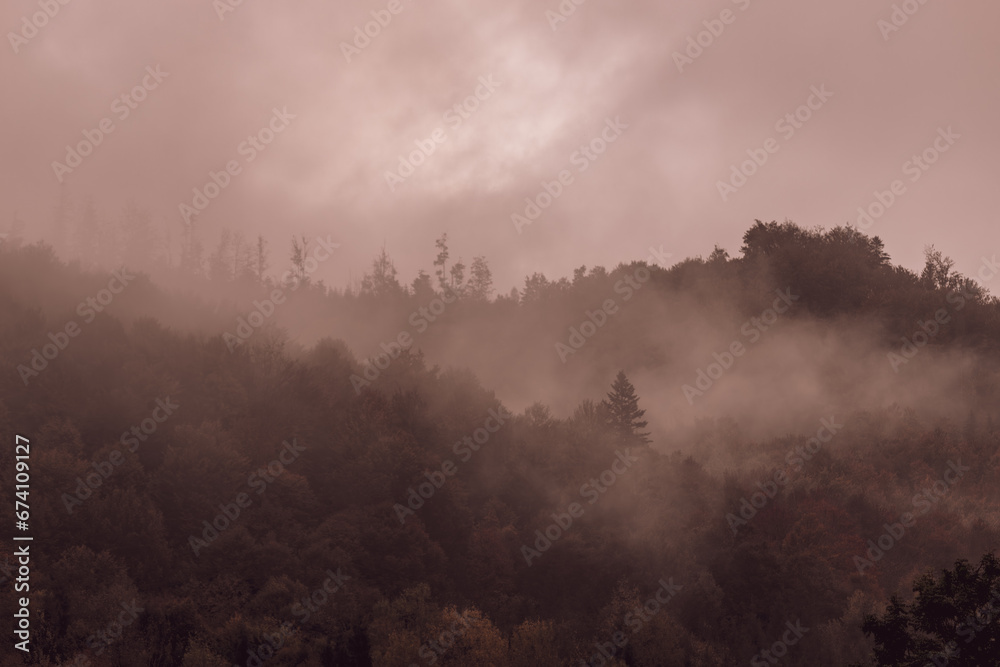 Silhouette of dark mountains and forest in mystical landscape. Mystical landscape. Fog in the mountains. Silhouettes of mountains. Morning mist in the forest among the hills. Gloomy mood.