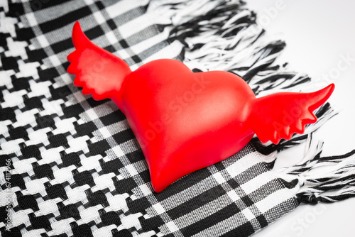 Red heart with wings on the traditional Middle Eastern and Arabic headdress Keffiyeh close-up. photo