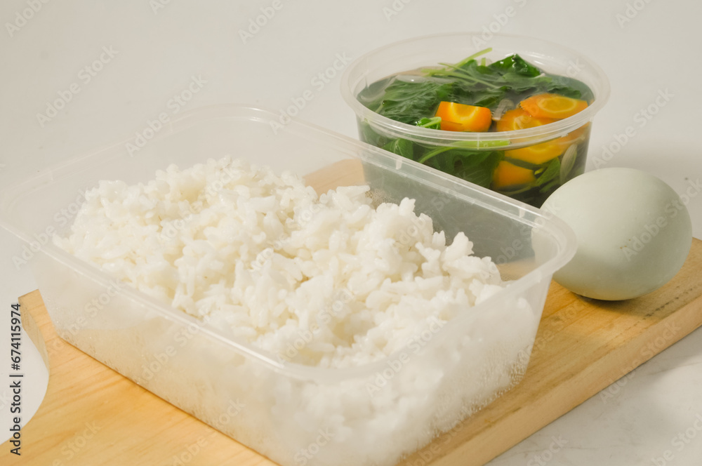 a menu of white rice with clear vegetables of spinach leaves and carrots and a salted egg on a wooden board isolated on a white background a menu of white rice with clear vegetables of spinach leaves and carrots and a salted egg on a wooden board isolated on a white background