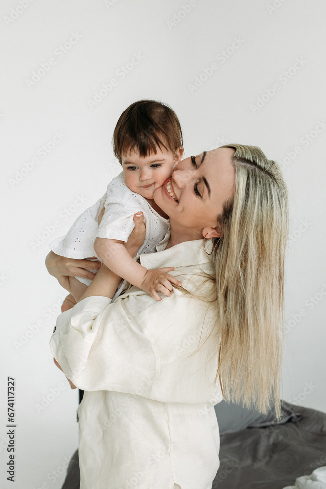 Mom holds her one-year-old daughter in her arms, hugs her, and rejoices. Mom holds her one-year-old daughter in her arms, hugs her, and rejoices.