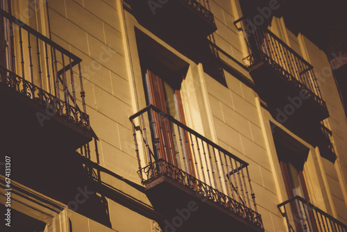 Madrid, Spain. Facade, wall of a yellow old apartment building in a city center. Spanish architecture in sunny day. Travel postcard. Balconies and windows on a house facades in sunset sunshine.