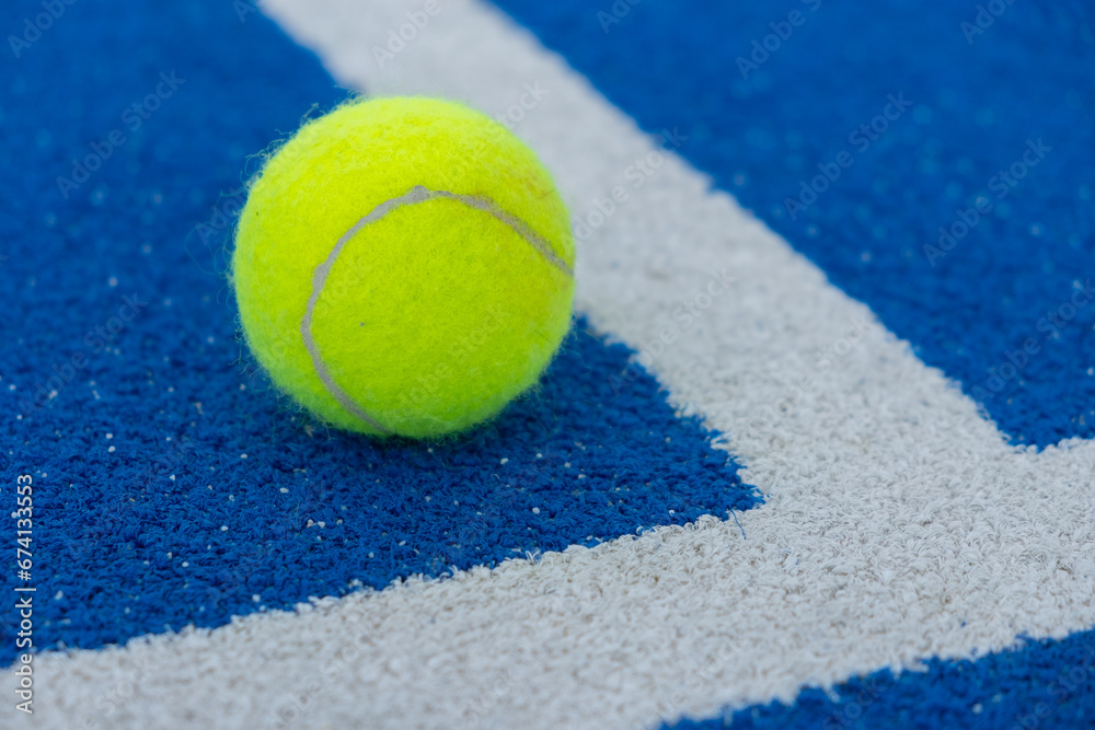 paddle tennis ball at the corner of the lines of a blue paddle tennis court
