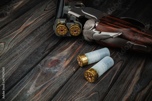 Classic trigger double-barreled hunting rifle on a wooden background. Concept postcards for hunters. Smooth-bore hunting rifle open for reloading. photo
