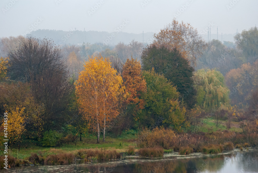 Autumn atmosphere. Yellow trees in the fog on the shore of an autumn lake. Autumn atmosphere. Yellow trees in the fog on the shore of an autumn lake.